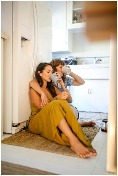 A happy couple sitting on the kitchen floor enjoyi