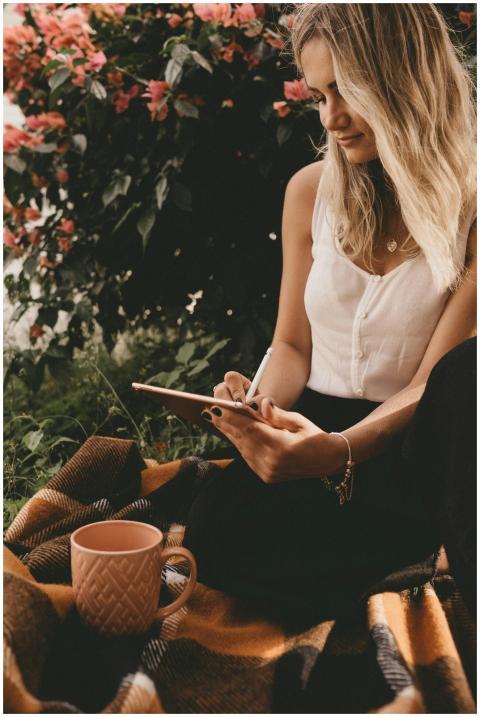 Young woman writing on tablet while relaxing outdo