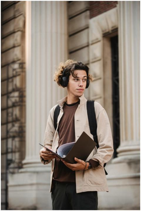 Thoughtful young man with headphones holding a fol