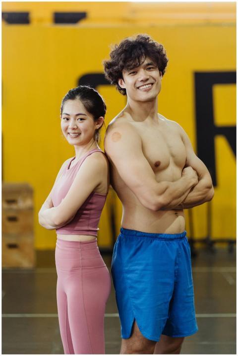 Smiling young woman and man standing back to back