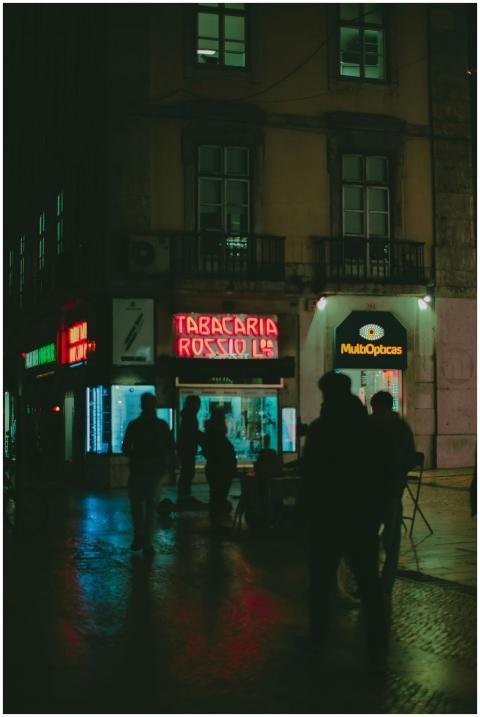 Silhouetted people walk through an illuminated urb