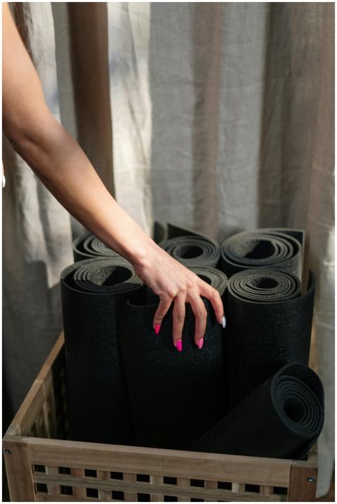 Close-up of a hand selecting a yoga mat from a bas