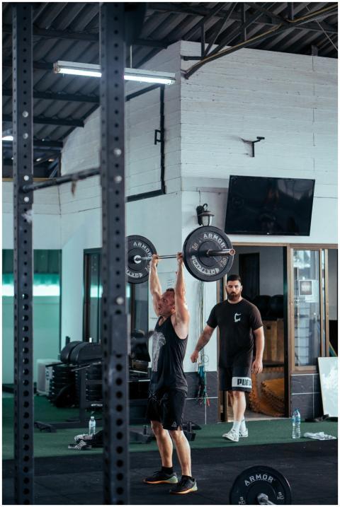 A man lifting a barbell in a modern gym with gym e