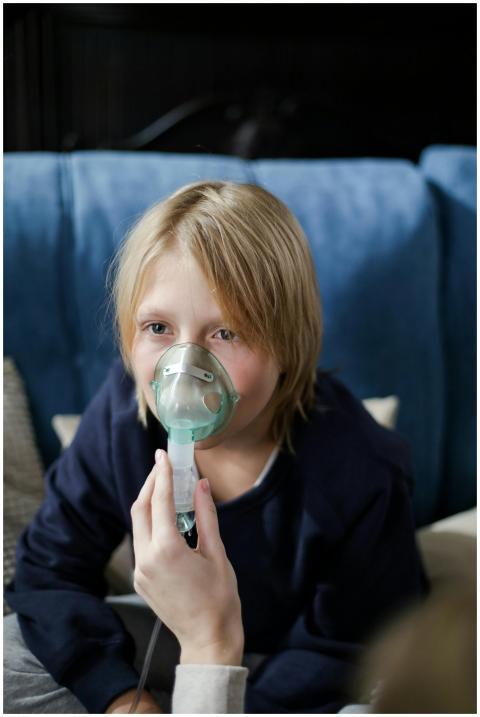 Young child sitting on a sofa while receiving inha