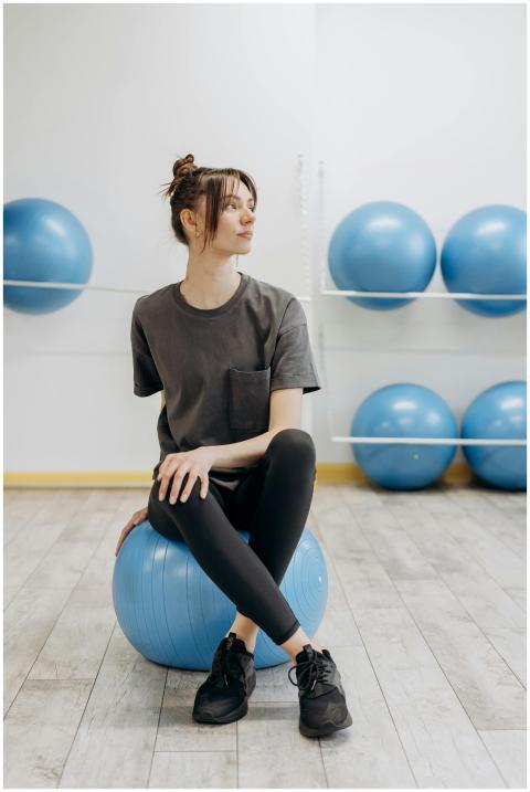 A woman sitting on a yoga ball indoors, promoting