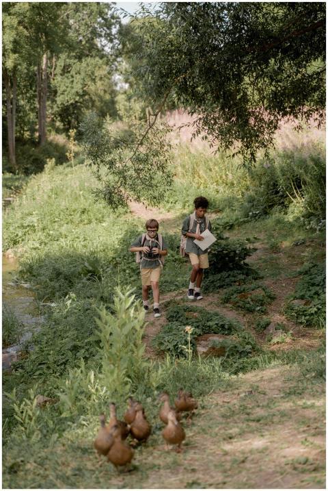 Two young boys walking through forest with map and