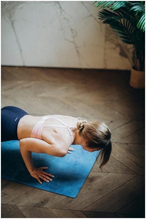 Adult woman performing yoga push-up pose on mat in