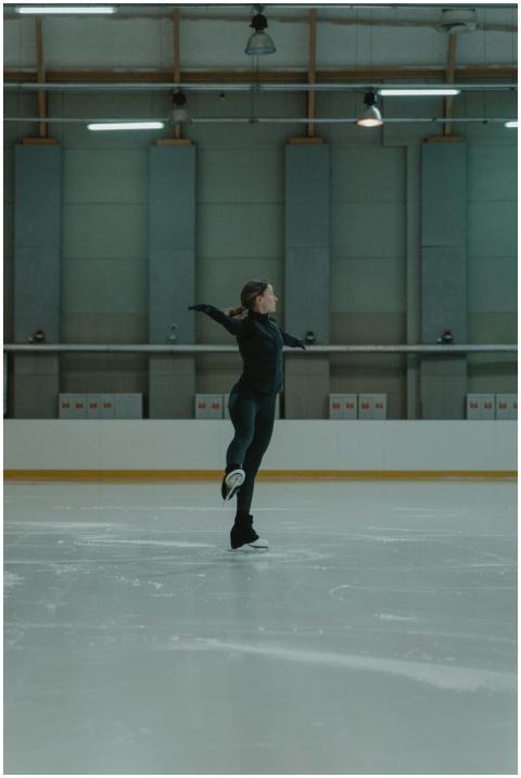 A figure skater performing a move on an indoor ice