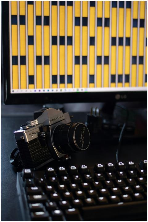A vintage camera placed beside a modern computer d
