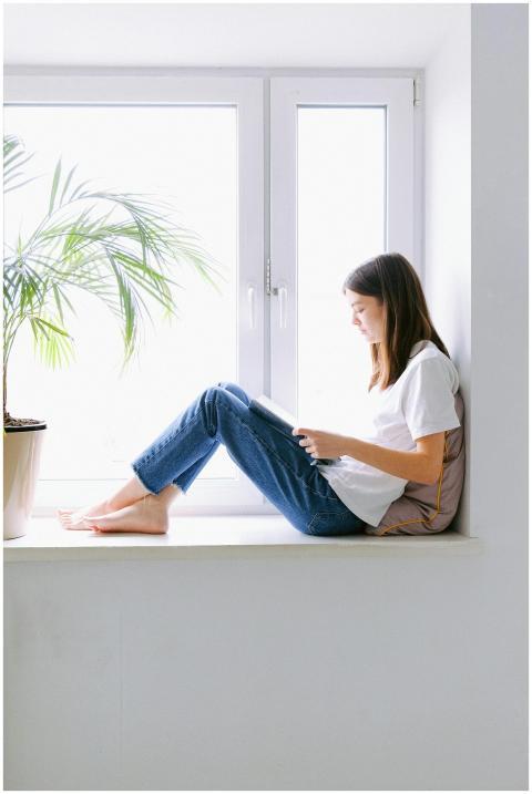 Teen girl enjoying a book while sitting by a brigh