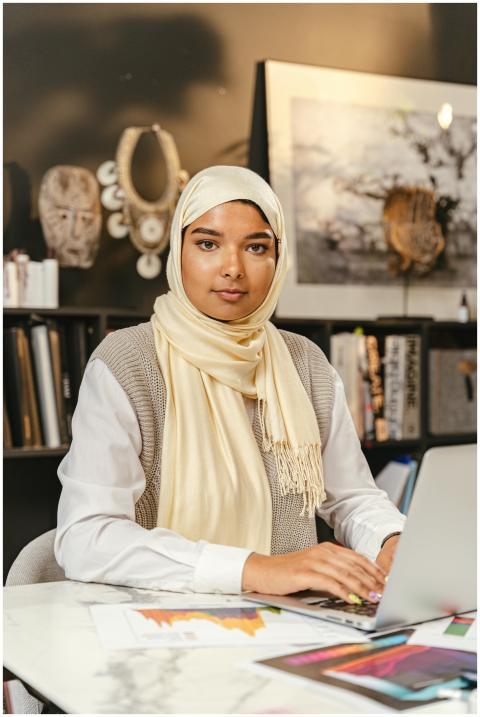 Confident woman wearing hijab working on a laptop