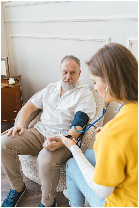 An elderly man having his blood pressure checked b