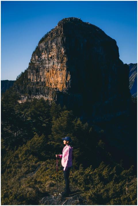 Woman in pink jacket hiking near a large rock form
