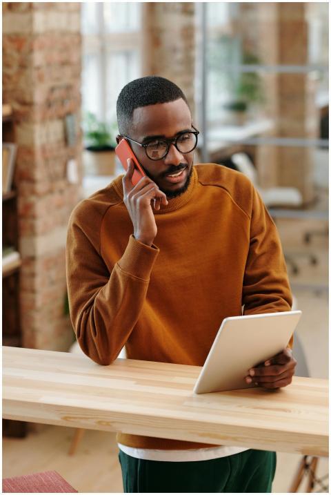 Young man in a modern office multitasking with a d