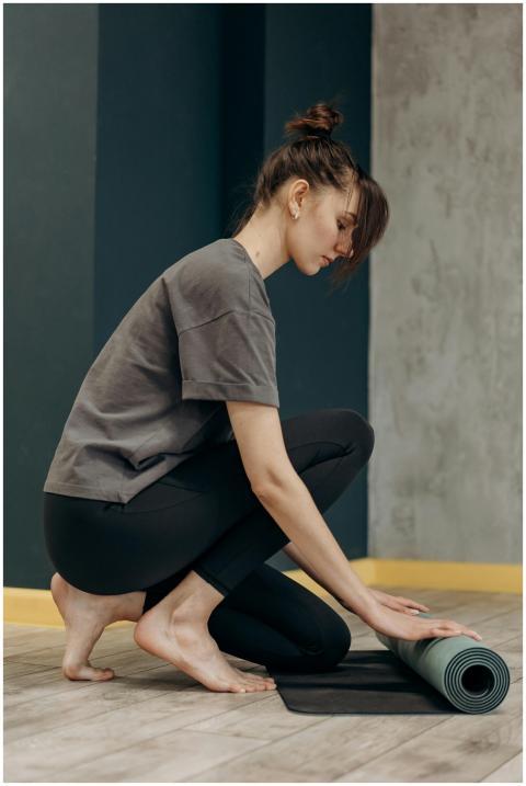 Woman setting up her yoga mat indoors, ready for a