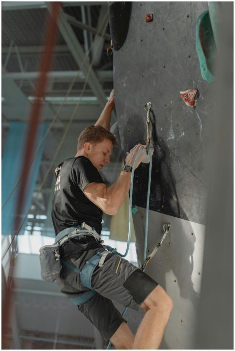 A man confidently rock climbing indoors, showcasin