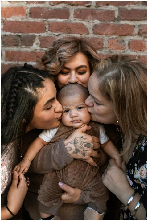 Three women lovingly embrace a baby, exemplifying