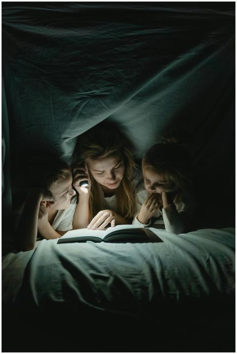 Mother reading a book to her children under a cozy
