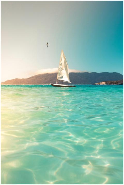 A sailboat glides across turquoise seas beneath a