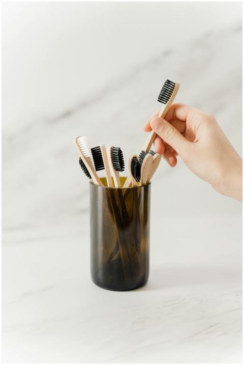 A hand selecting a wooden toothbrush from an eco-f