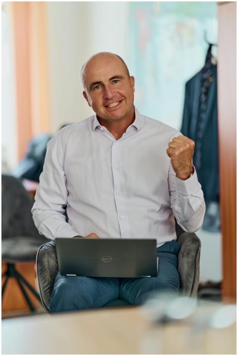 Smiling businessman in an office holding a laptop,