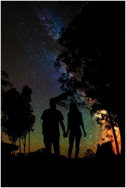 A couple's silhouette under a vibrant starry sky i