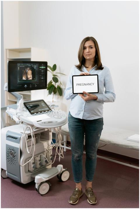 A woman holding a tablet displaying 'Pregnancy' be