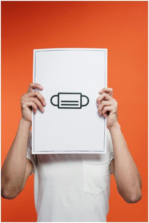 Person holding a poster with a mask illustration a
