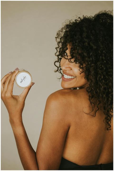 Smiling woman presenting a Misolo skincare product