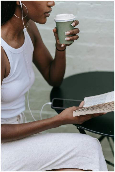 A woman enjoys reading and sipping coffee at an ou
