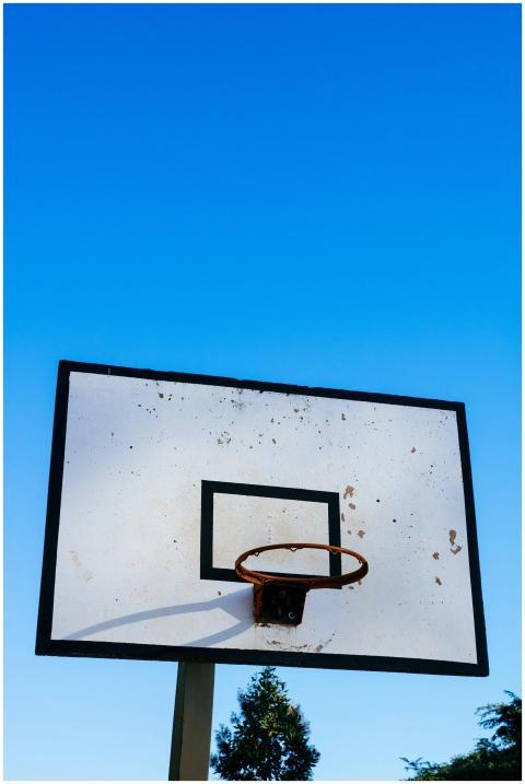 A rustic basketball hoop and backboard under a cle