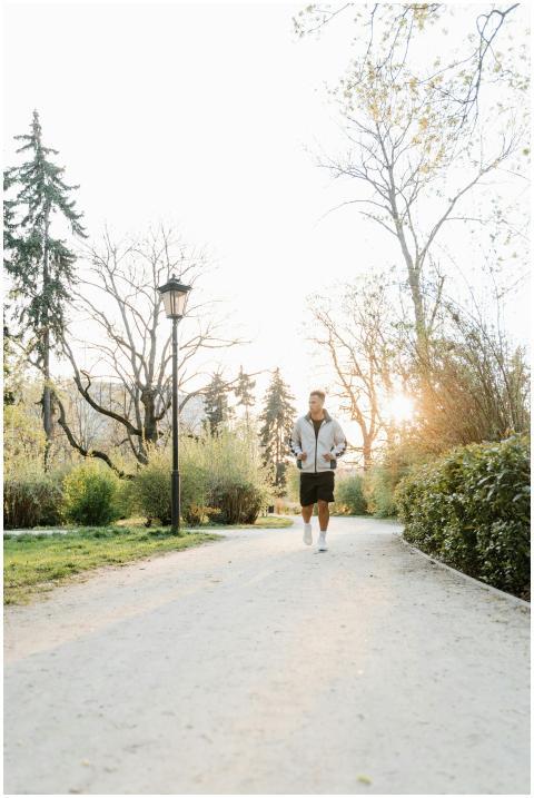 A person jogging in a sunlit park with trees, capt