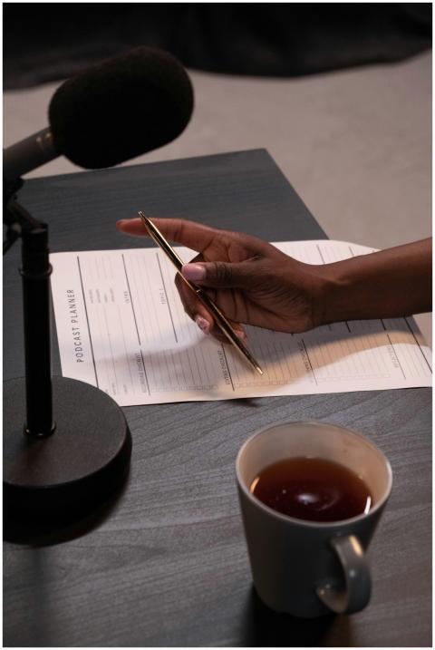 Close-up of hand holding pen near microphone with