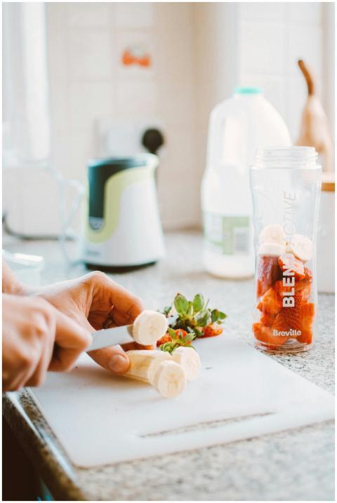 Preparing fresh smoothie with sliced banana and st