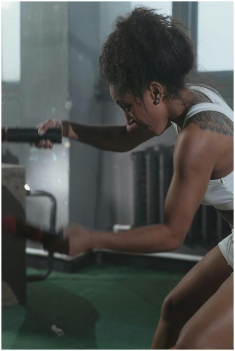 Focused woman exercising with battle ropes in a gy