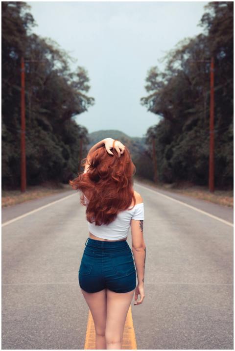Red-haired woman in jean shorts walking down a for