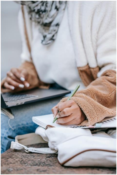 Young woman studying outdoors, using a laptop and