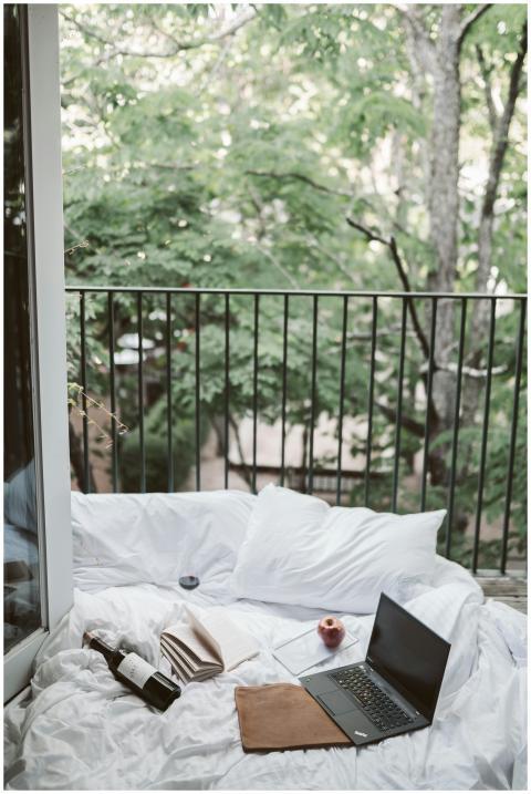 Relaxing on a cozy balcony with a laptop and wine