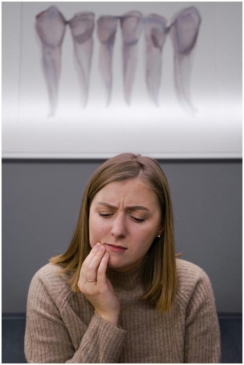 A concerned adult woman with a toothache sits in a