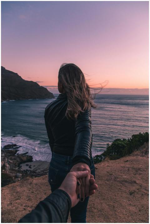 Young couple holding hands by the ocean with a stu