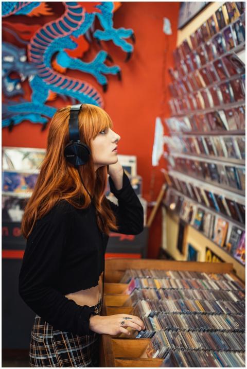 Young woman with headphones selecting music CDs in