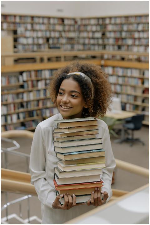 Happy woman with afro hair carrying a stack of boo
