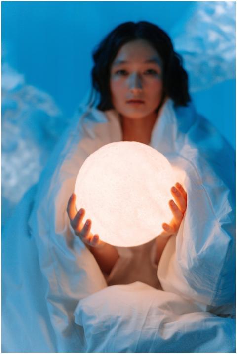 A person holds a glowing orb in a conceptual, drea