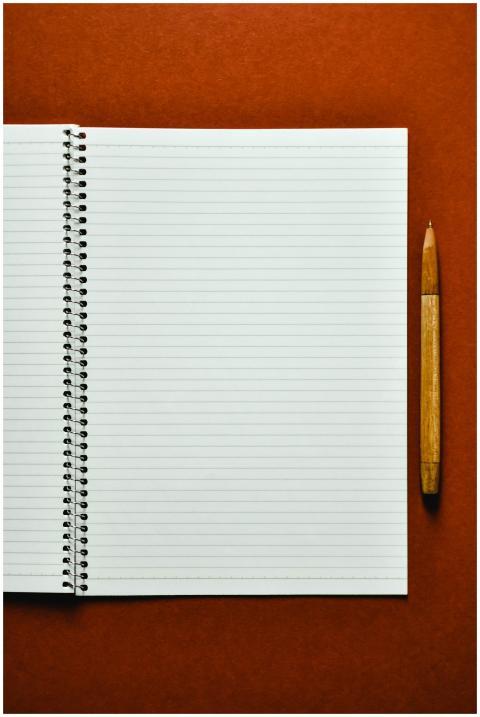 Open spiral notebook and wooden pen on orange surf