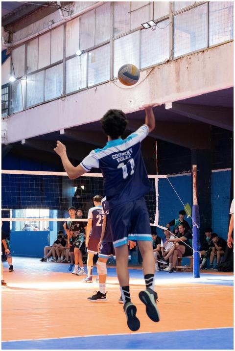 Player jumps to hit volleyball during indoor game,