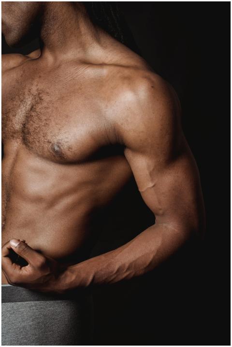 Close-up of a shirtless man flexing his bicep, sho