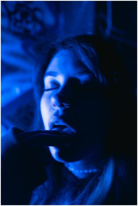 A vivid, moody portrait of a woman bathed in blue