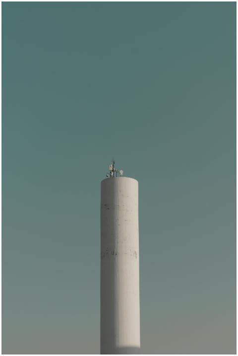 A tall white telecommunications tower stands again