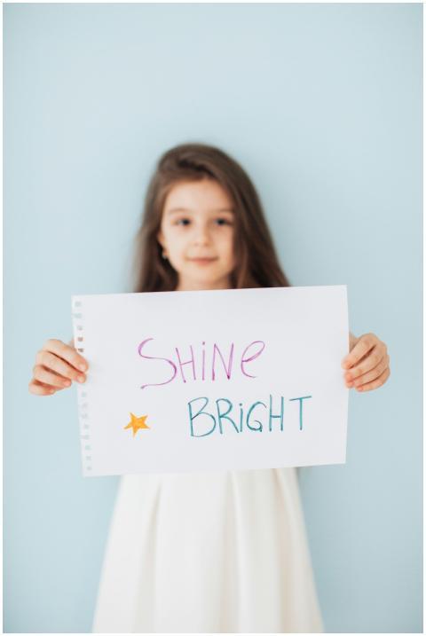 A young girl holding a motivational sign that says