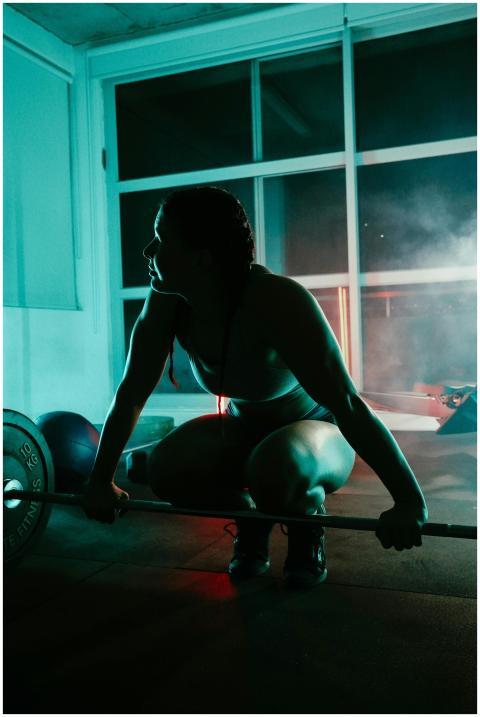 A woman preparing to lift weights at a gym under d